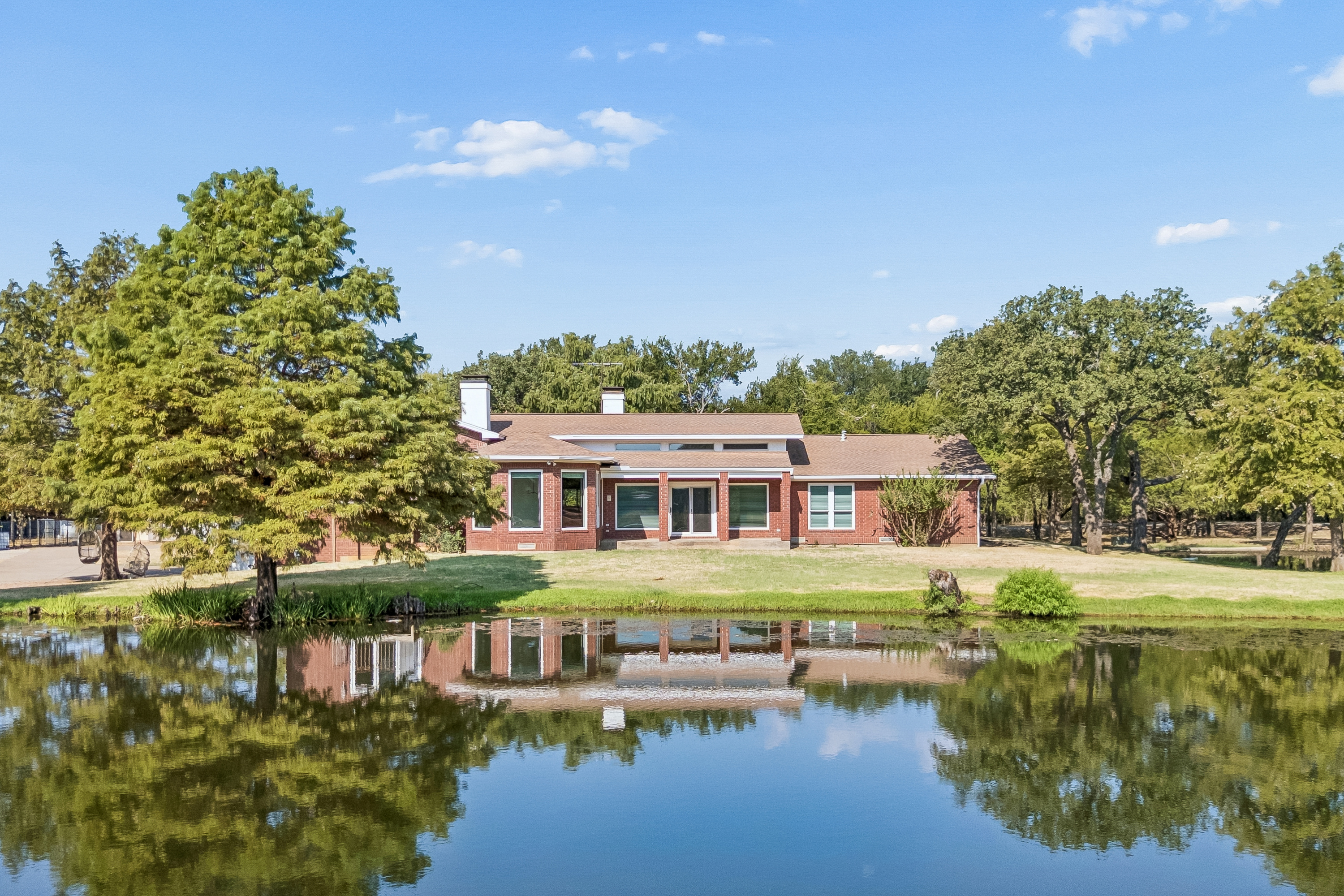 Point Vista Ranch residence reflected in the private stocked pond in Hickory Creek, Texas